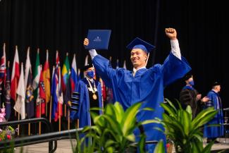 UK grad holding his diploma on stage